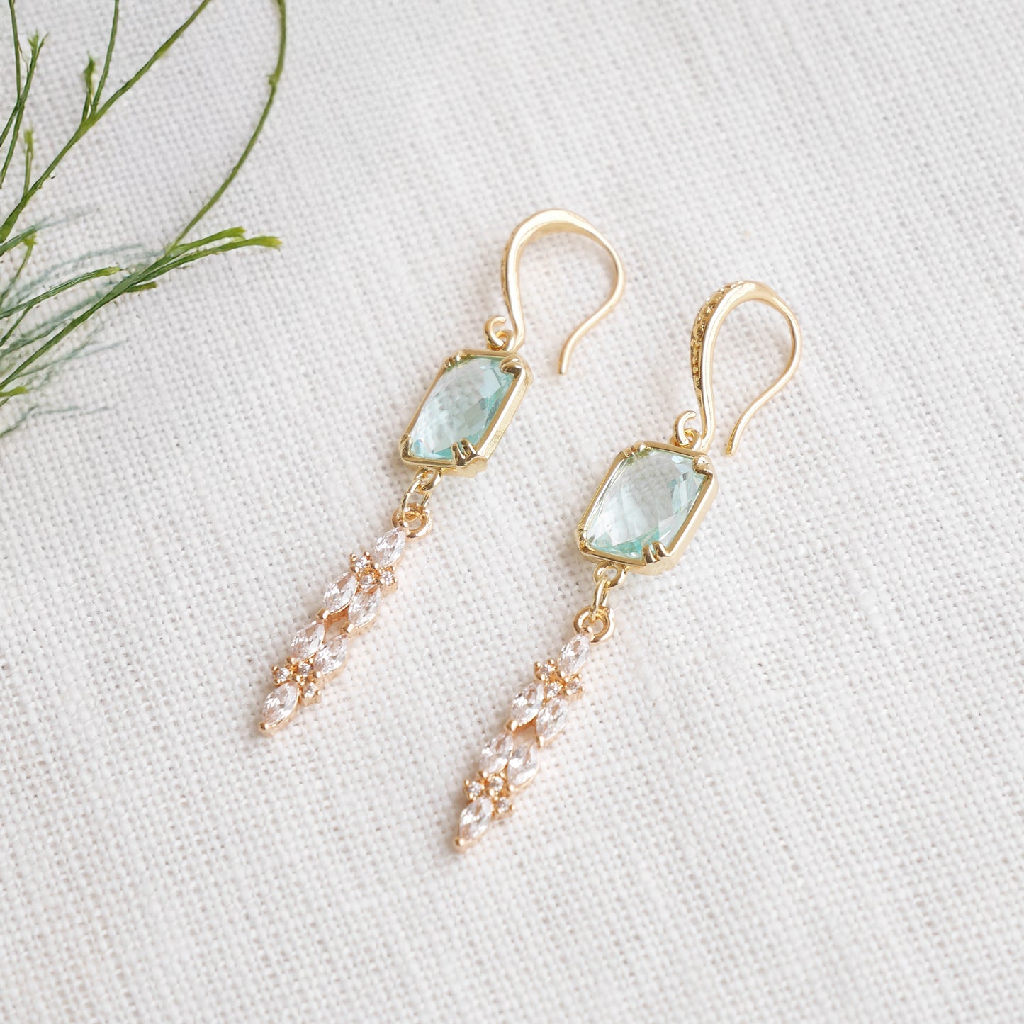 Long light blue glass bridal dangle earrings on a white cloth.