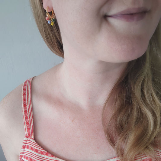 Woman wearing colorful striped hoop earrings.