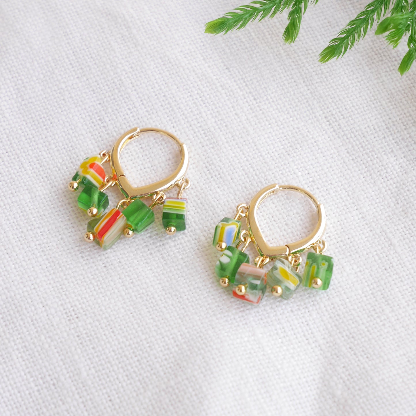 Green glass chip hoop earrings on a white cloth.