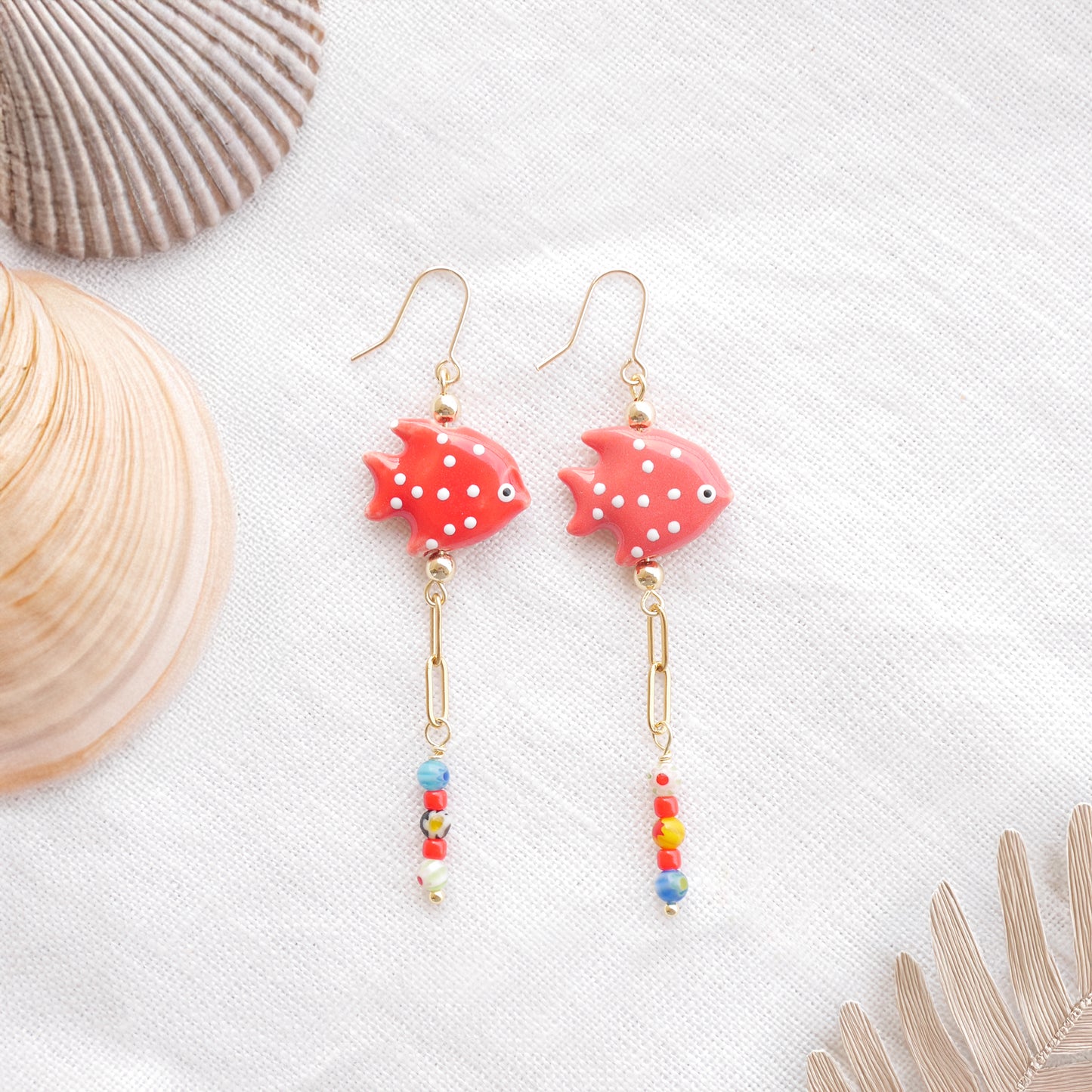 Red fish dangle earrings on a white cloth