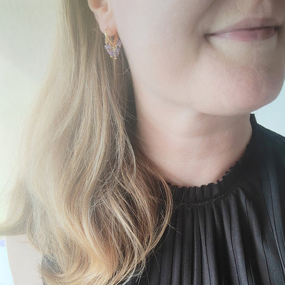 Woman wearing amethyst hoop earrings.