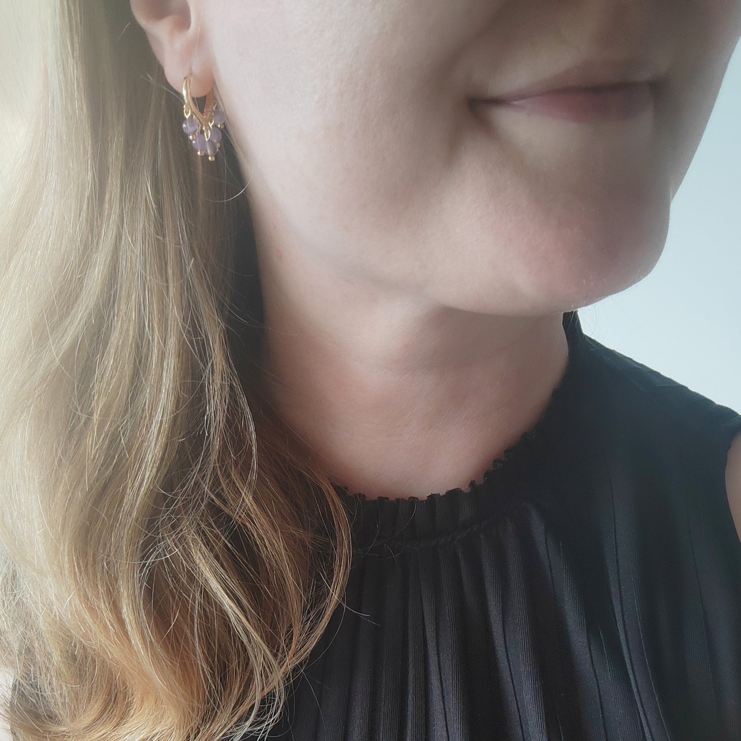Woman wearing amethyst hoop earrings.