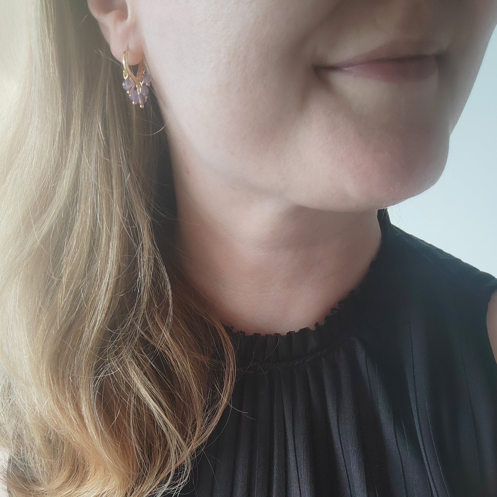 Woman wearing amethyst hoop earrings.