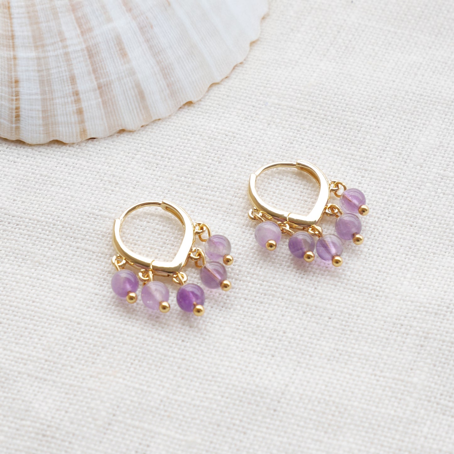 Amethyst hoop earrings on a white cloth.