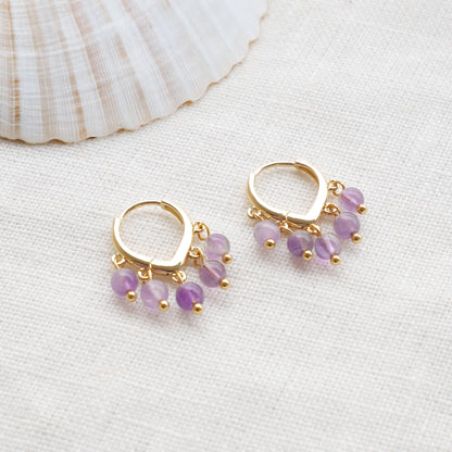 Amethyst hoop earrings on a white cloth.