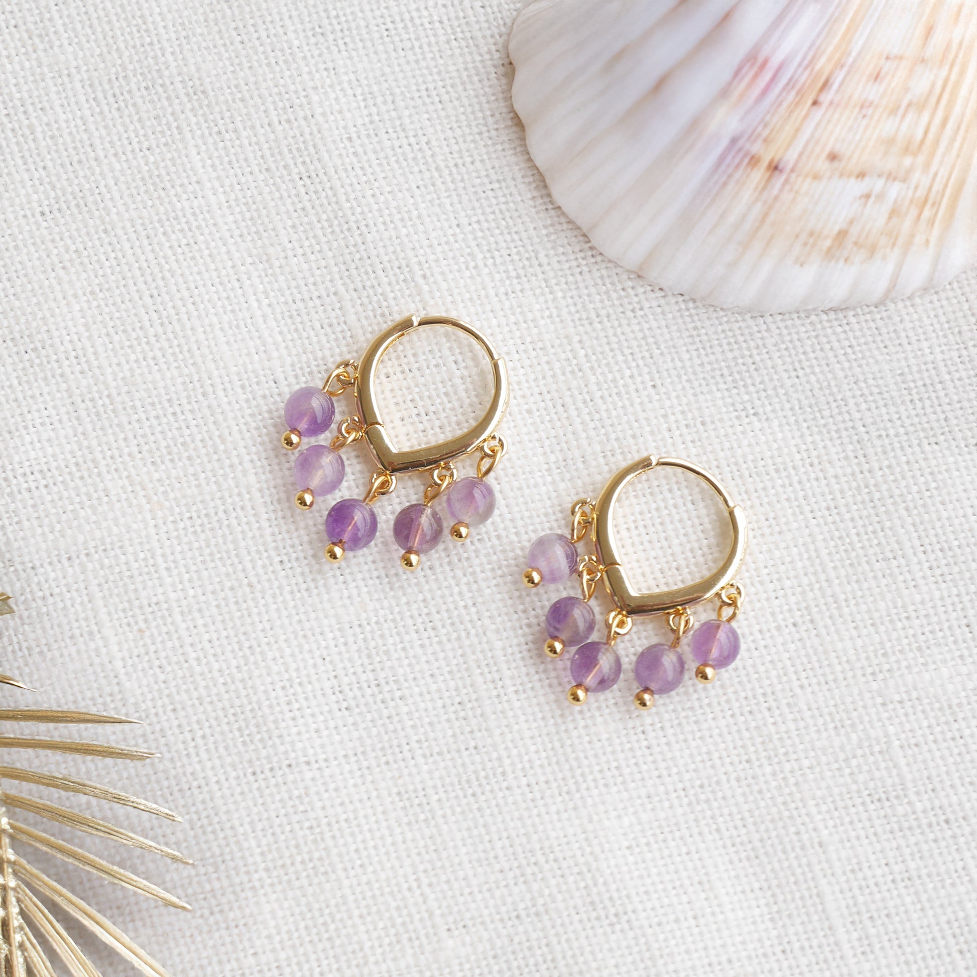Amethyst hoop earrings on a white cloth.