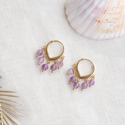 Amethyst hoop earrings on a white cloth.