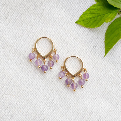 Amethyst hoop earrings on a white cloth.