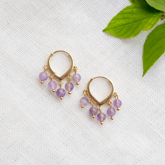 Amethyst hoop earrings on a white cloth.