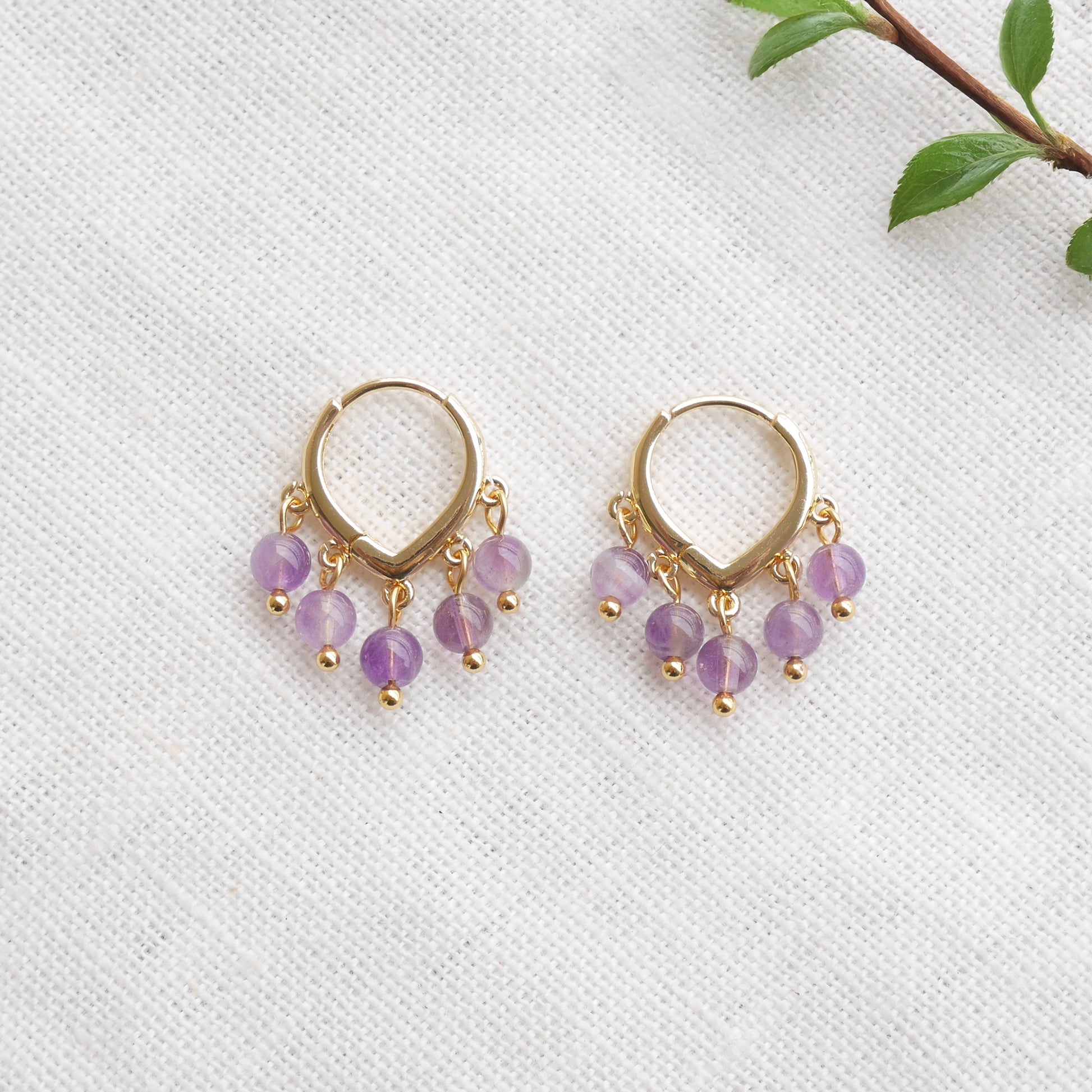 Amethyst hoop earrings on a white cloth.