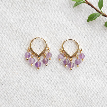 Amethyst hoop earrings on a white cloth.