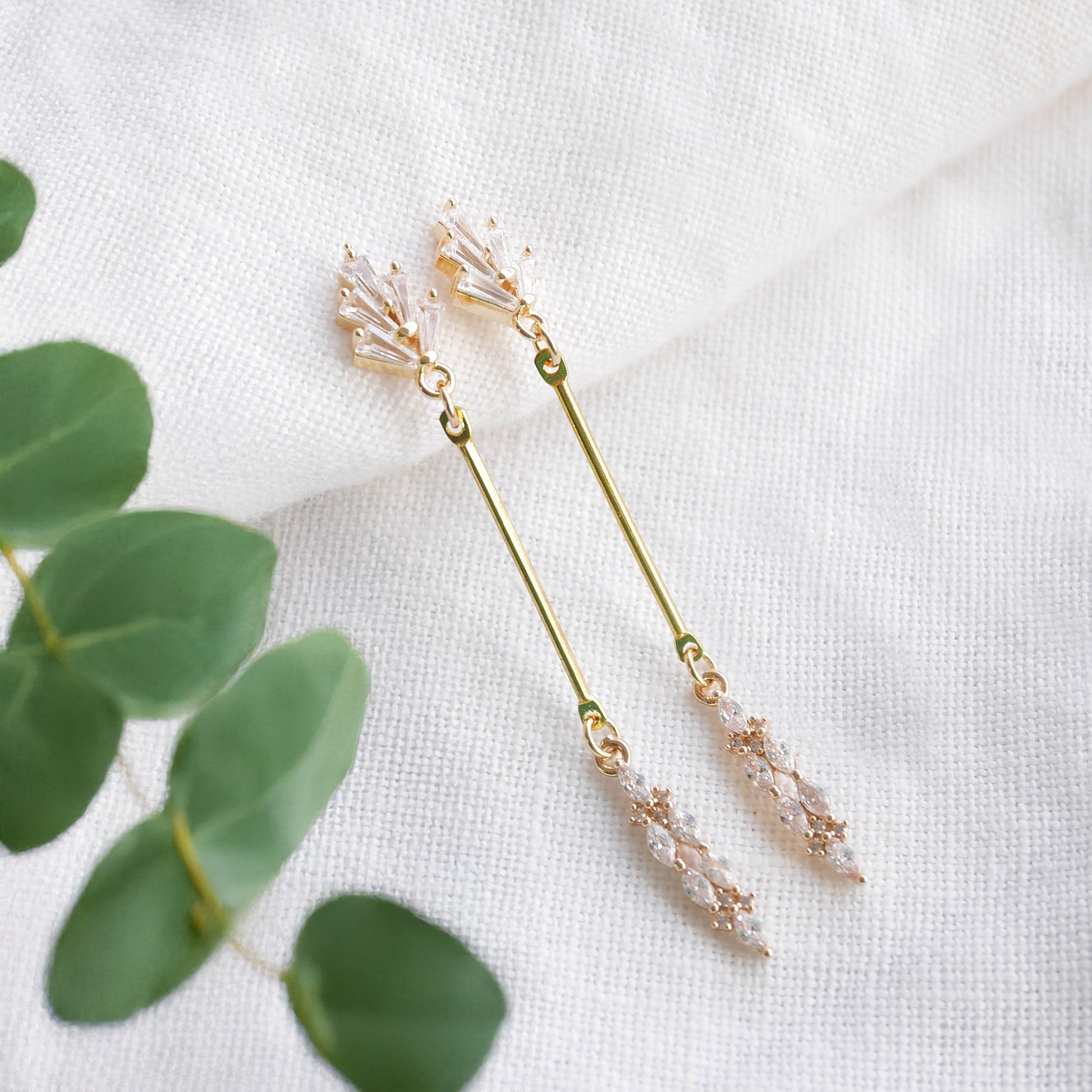 Art deco gold bar earrings on a white cloth.