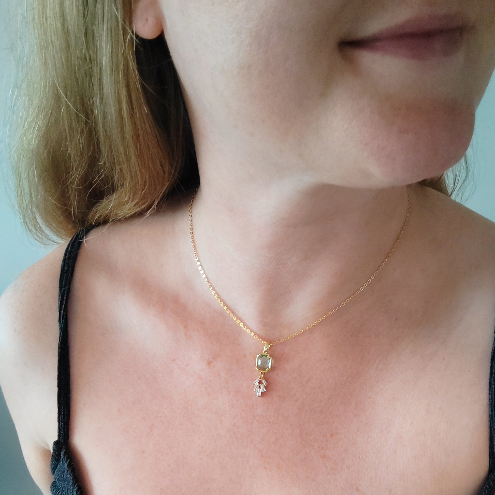 Woman wearing art deco style lake blue glass gold necklace.