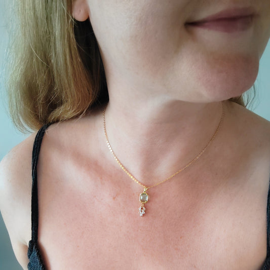 Woman wearing art deco style lake blue glass gold necklace.