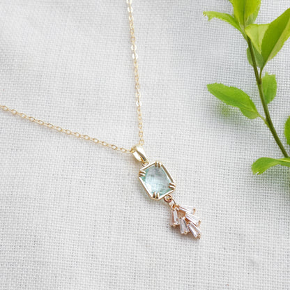 Art deco style lake blue glass gold necklace, on a white cloth.