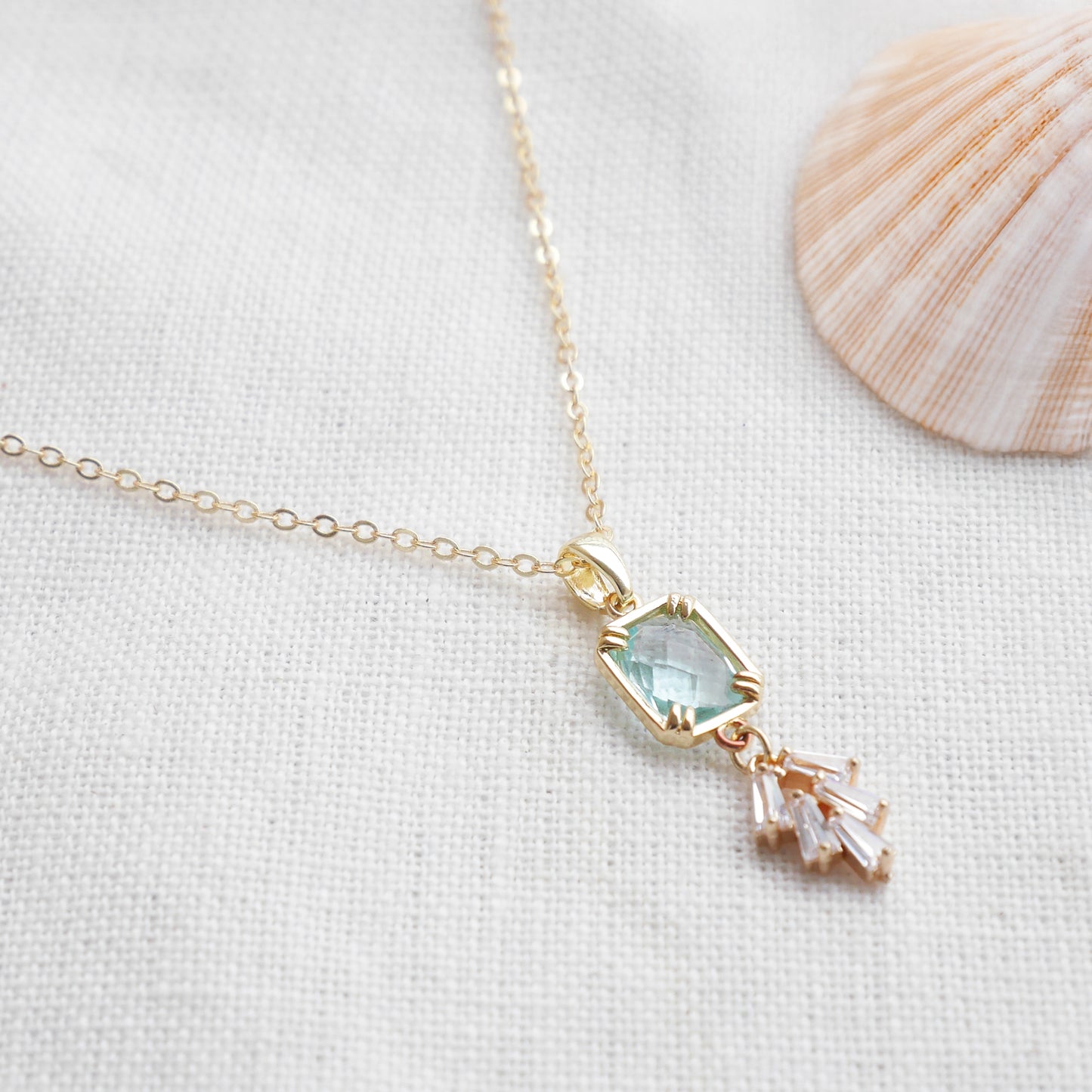 Art deco style lake blue glass gold necklace, on a white cloth.