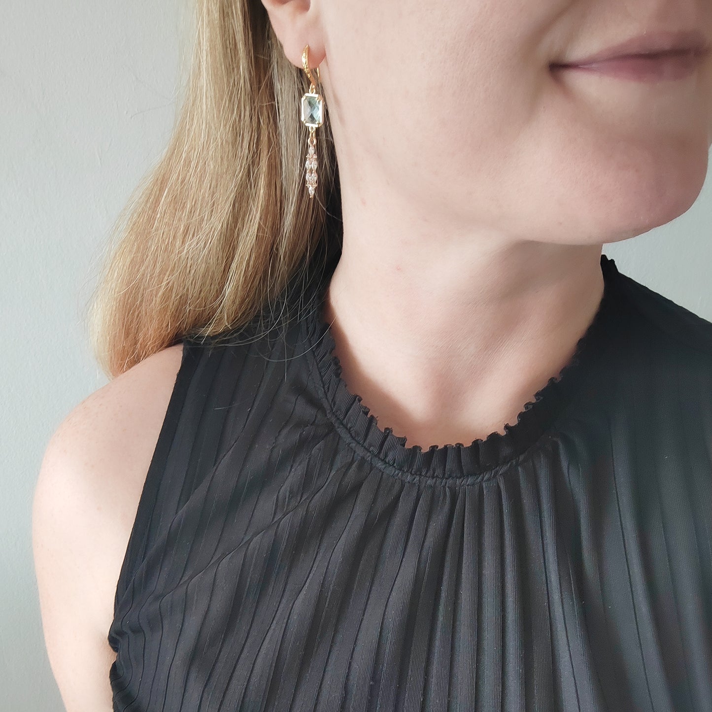 Woman wearing long light blue glass bridal dangle earrings.