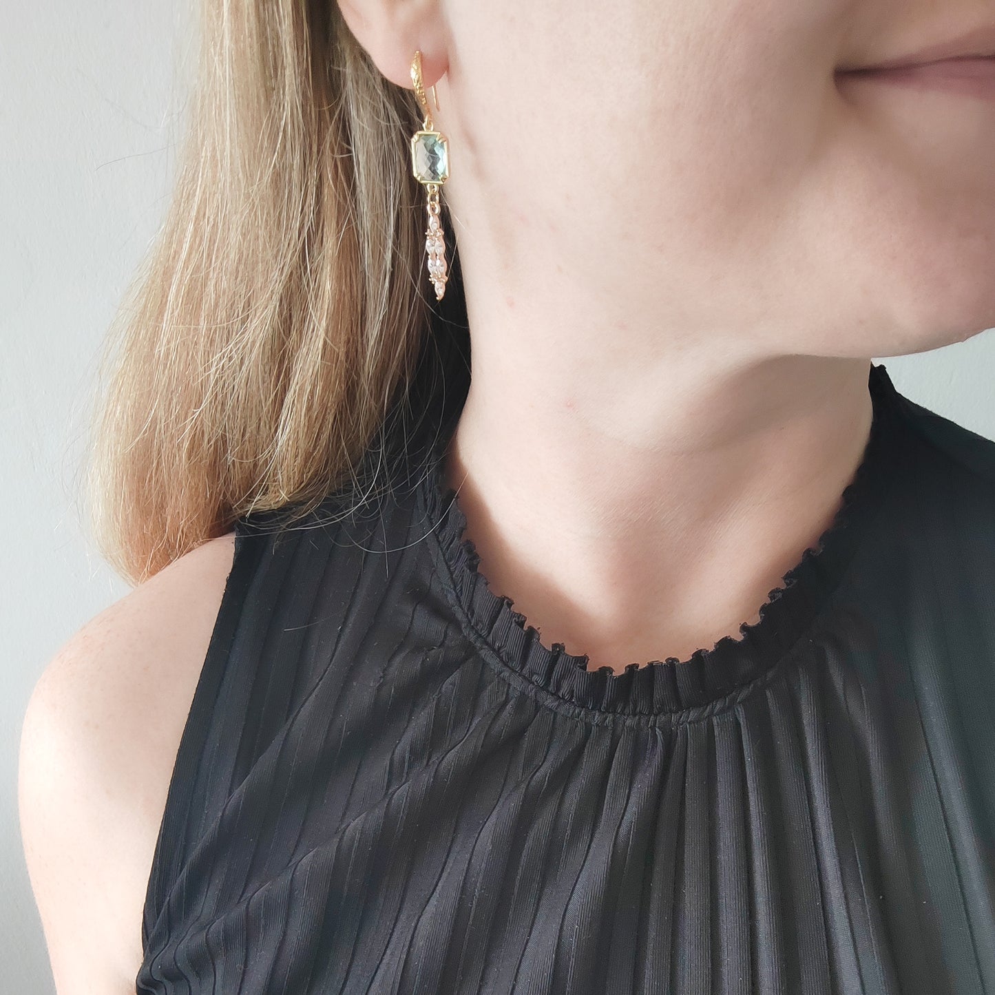 Woman wearing long light blue glass bridal dangle earrings.