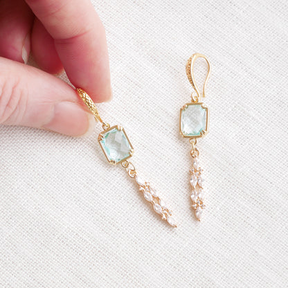 Long light blue glass bridal dangle earrings on a white cloth.