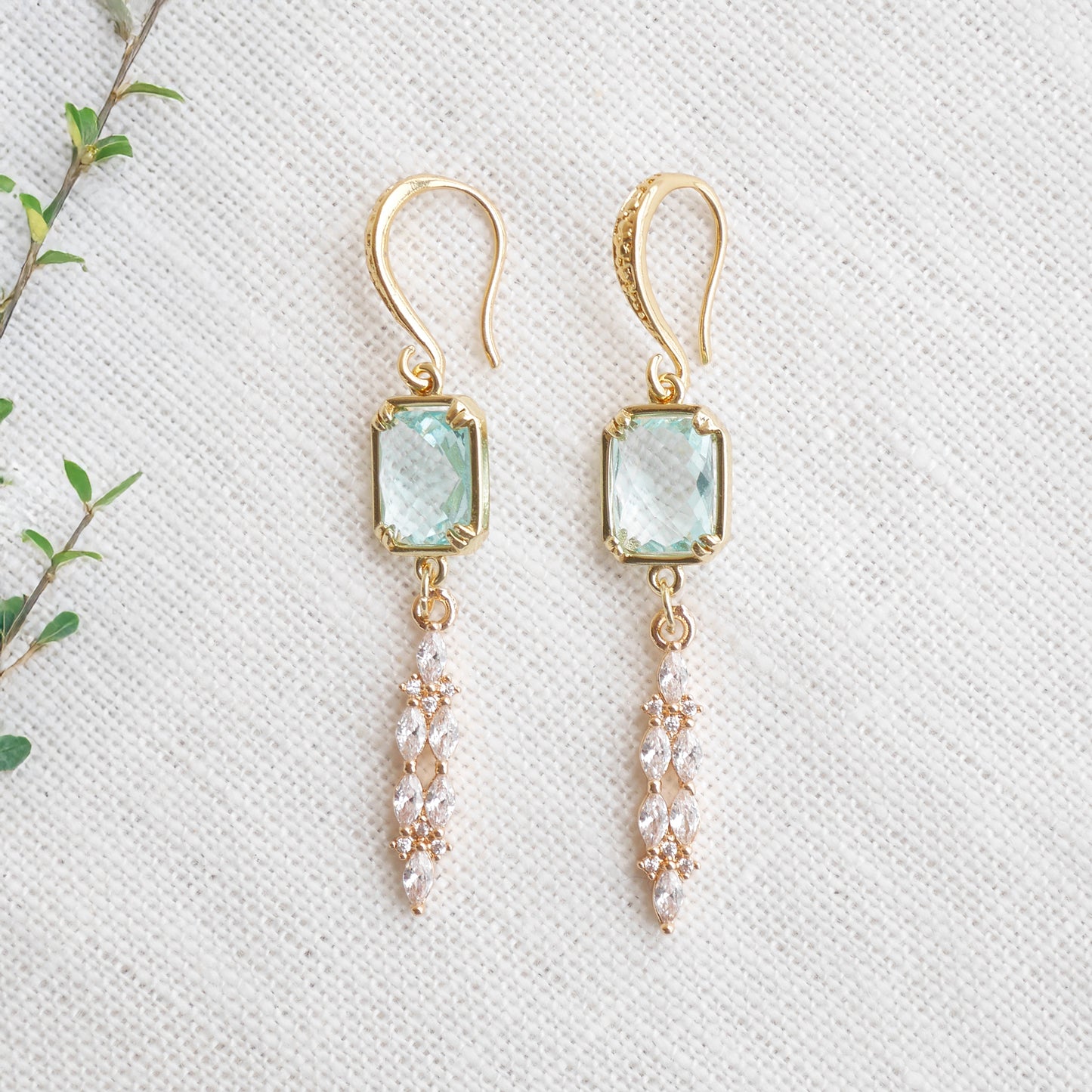 Long light blue glass bridal dangle earrings on a white cloth.