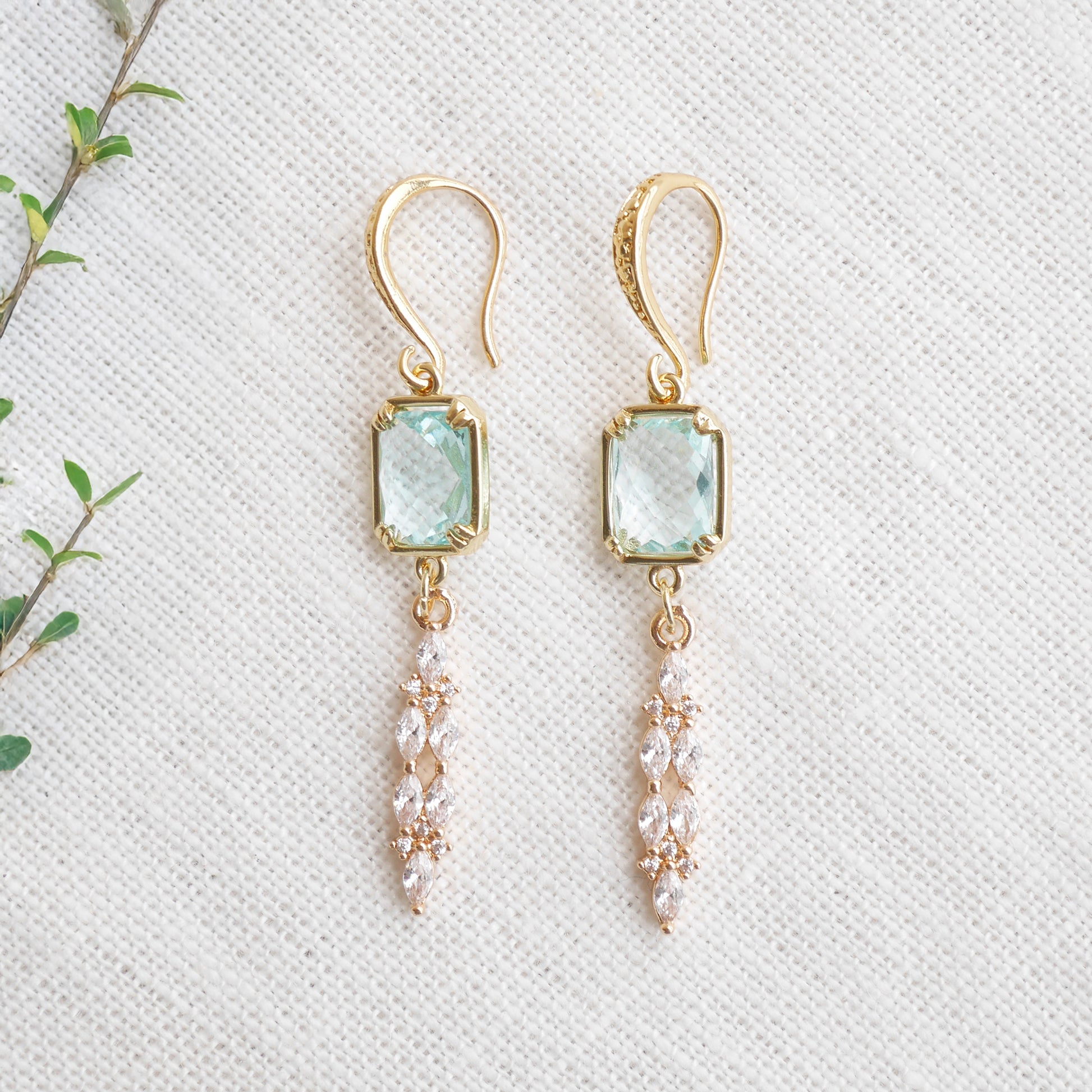 Long light blue glass bridal dangle earrings on a white cloth.
