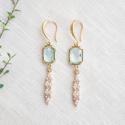 Long light blue glass bridal dangle earrings on a white cloth.