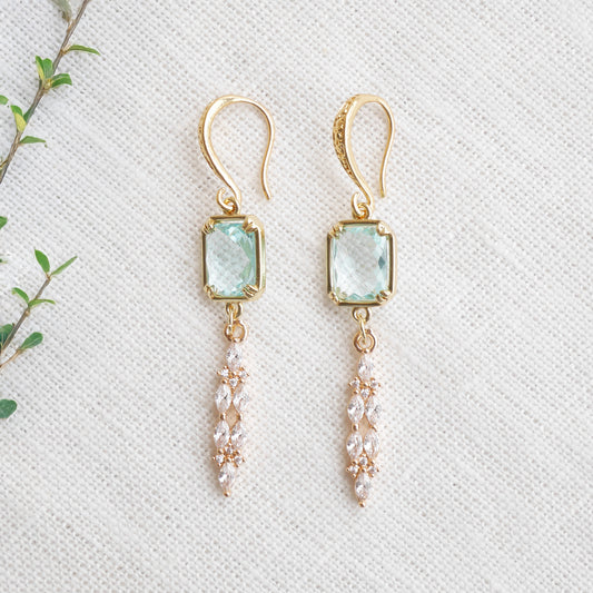Long light blue glass bridal dangle earrings on a white cloth.