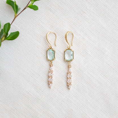 Long light blue glass bridal dangle earrings on a white cloth.