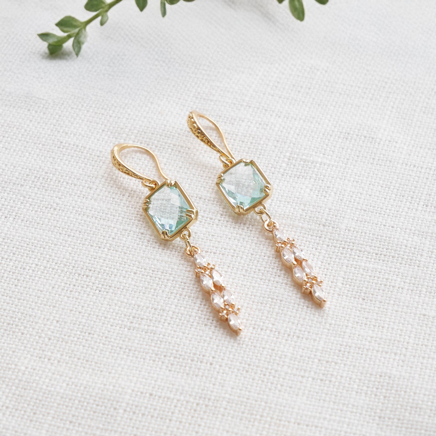 Long light blue glass bridal dangle earrings on a white cloth.