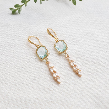Long light blue glass bridal dangle earrings on a white cloth.
