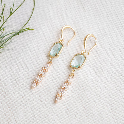 Long light blue glass bridal dangle earrings on a white cloth.