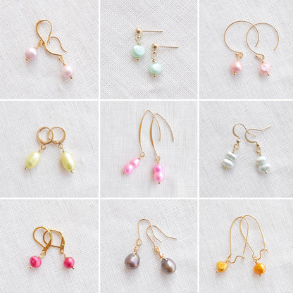 Nine pairs of colorful baroque freshwater pearl earrings on a white cloth.