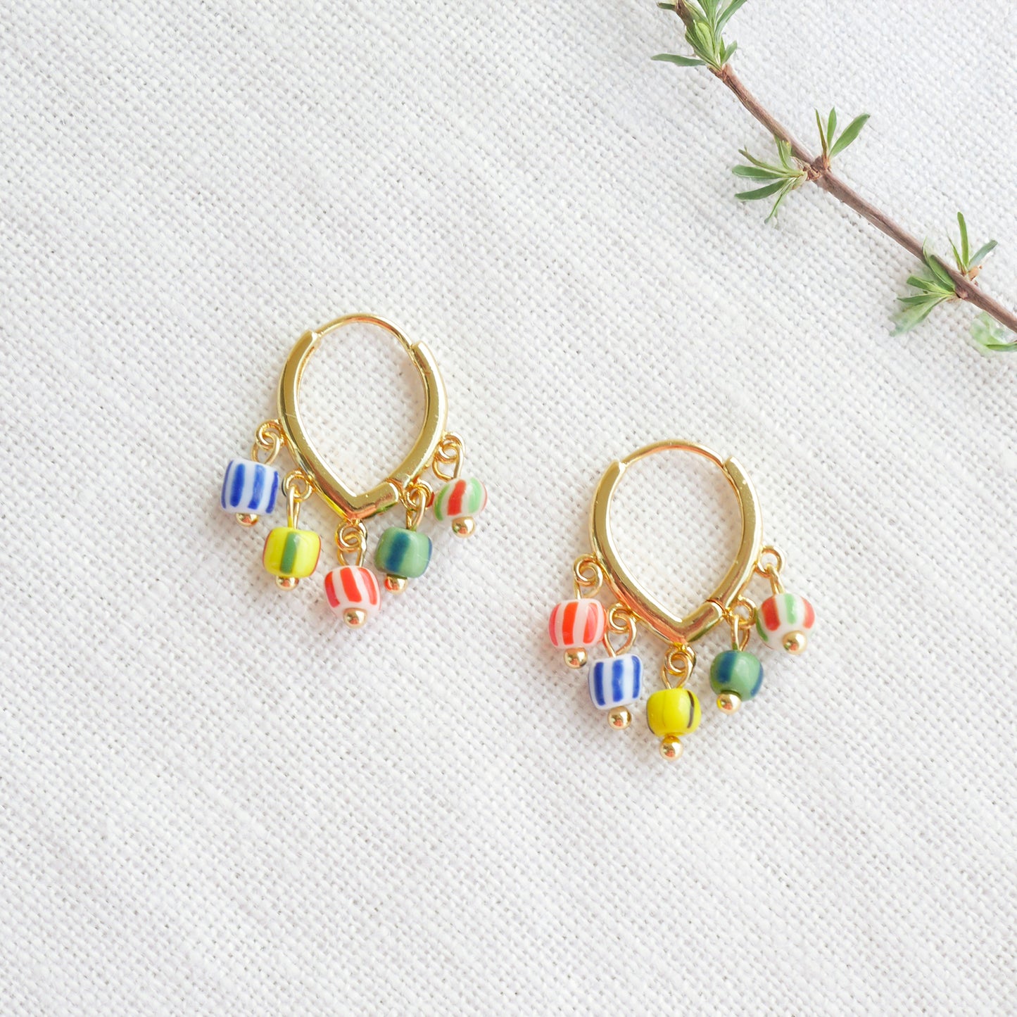 Colorful striped hoop earrings on a white cloth.