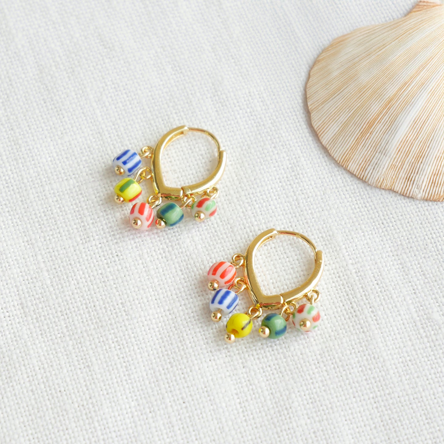 Colorful striped hoop earrings on a white cloth.