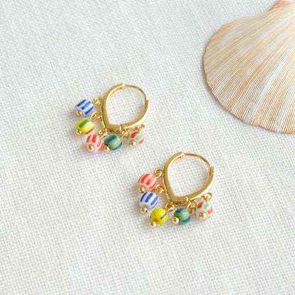 Colorful striped hoop earrings on a white cloth.