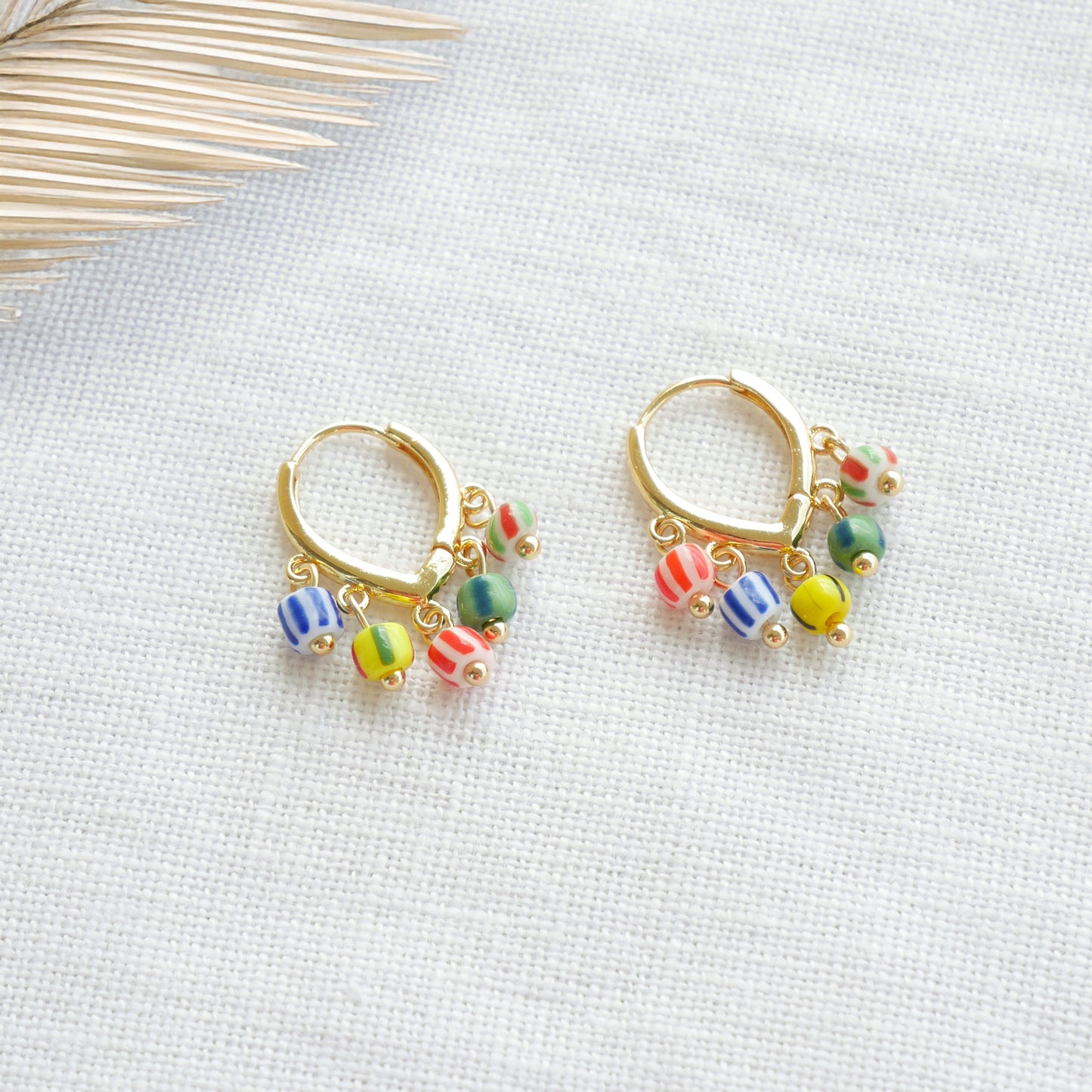 Colorful striped hoop earrings on a white cloth.