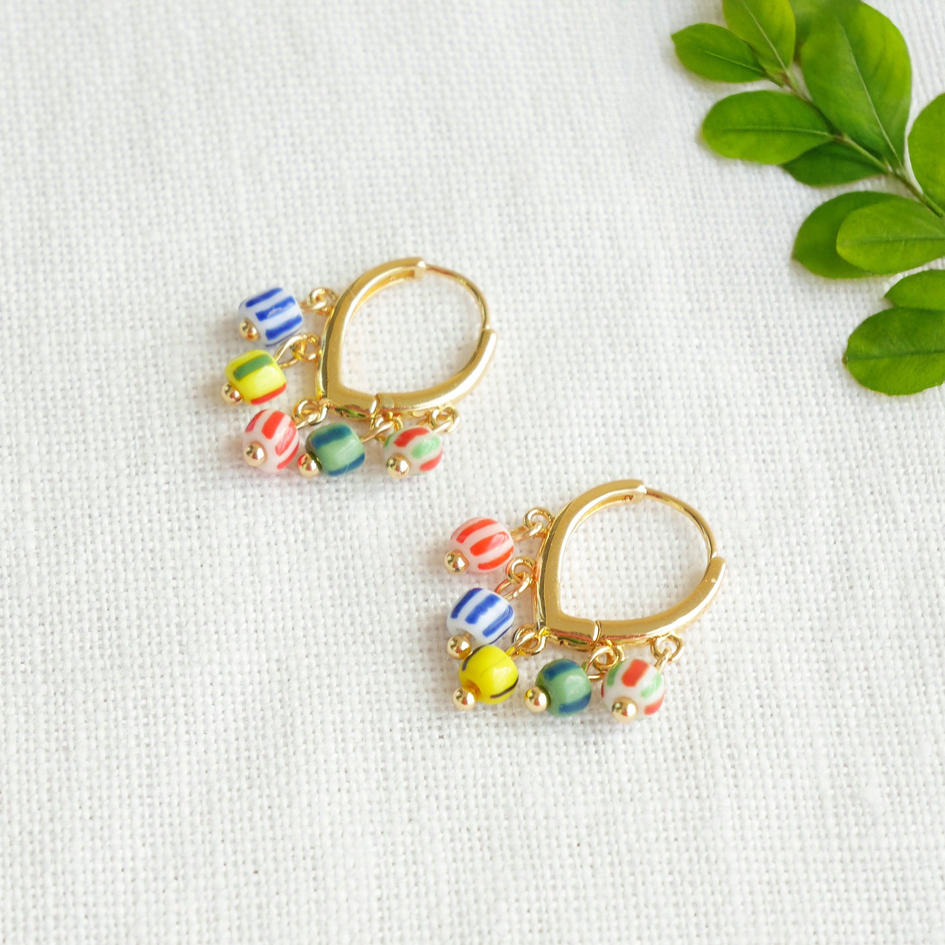 Colorful striped hoop earrings on a white cloth.