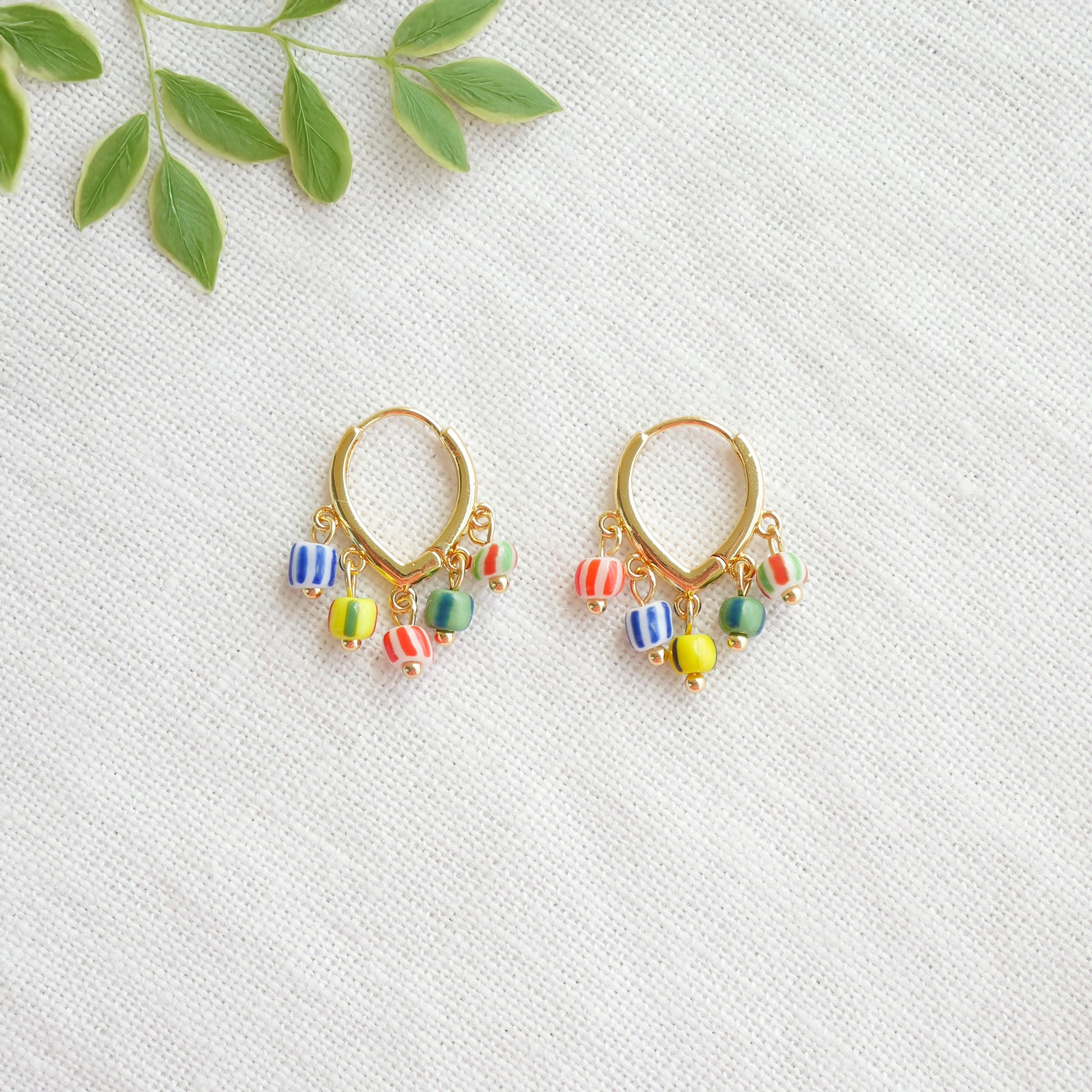 Colorful striped hoop earrings on a white cloth.