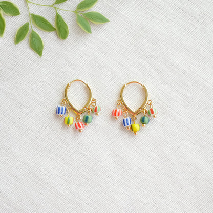 Colorful striped hoop earrings on a white cloth.