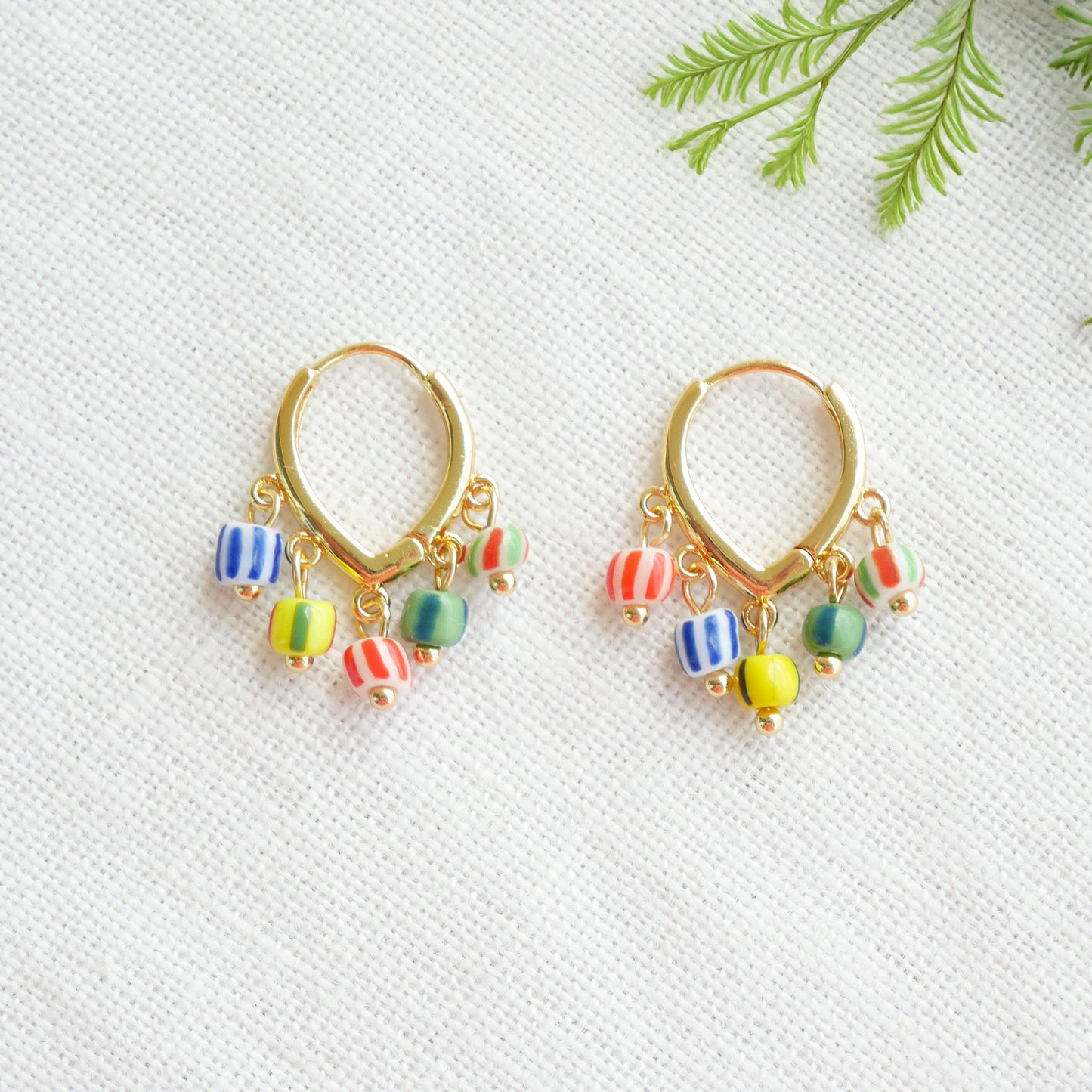 Colorful striped hoop earrings on a white cloth.