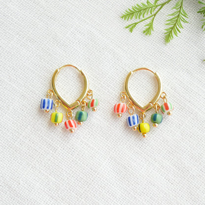 Colorful striped hoop earrings on a white cloth.