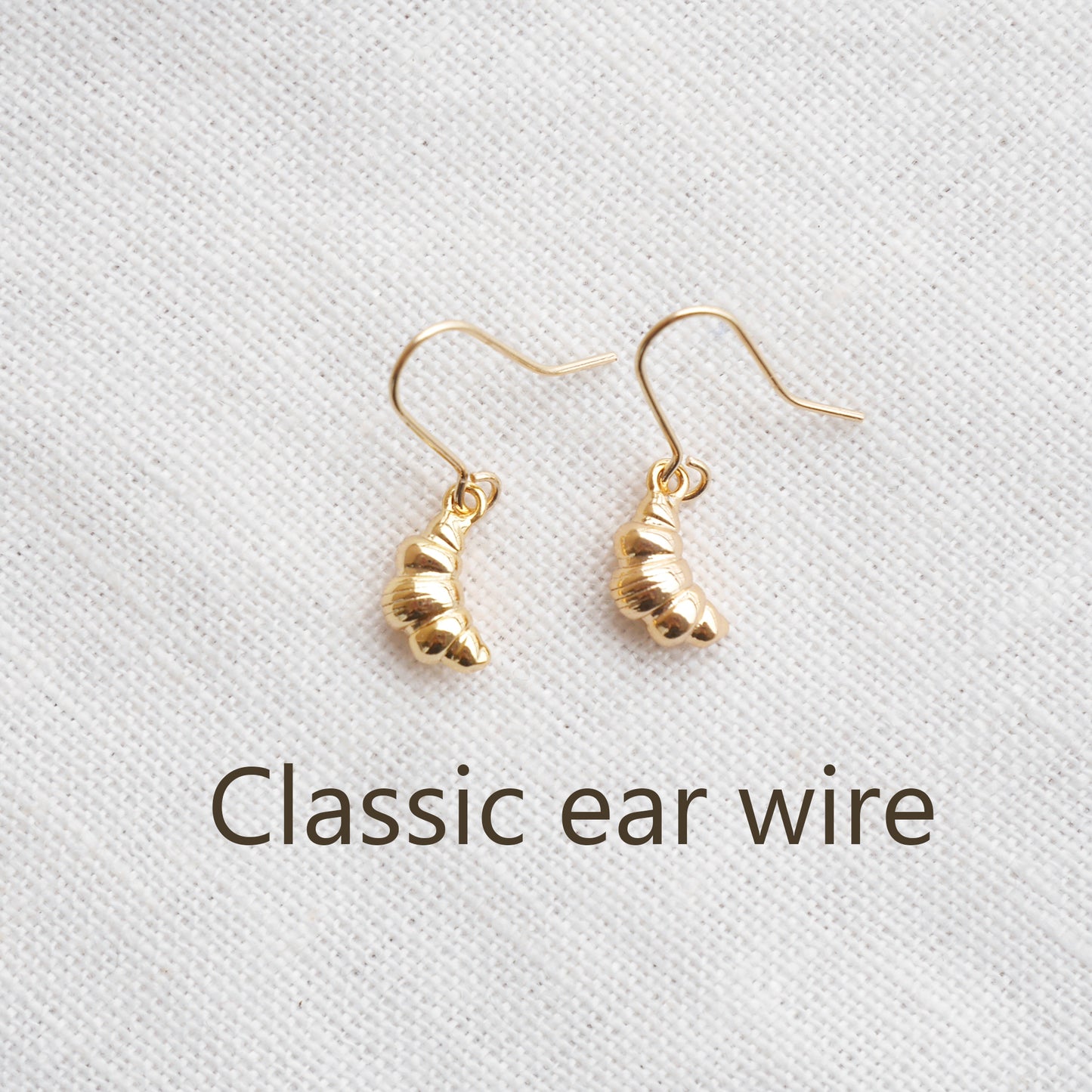 Gold croissant earrings on a textured white surface.