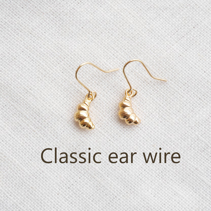Gold croissant earrings on a textured white surface.