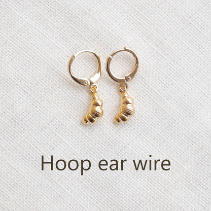 Gold croissant earrings on a textured white surface.