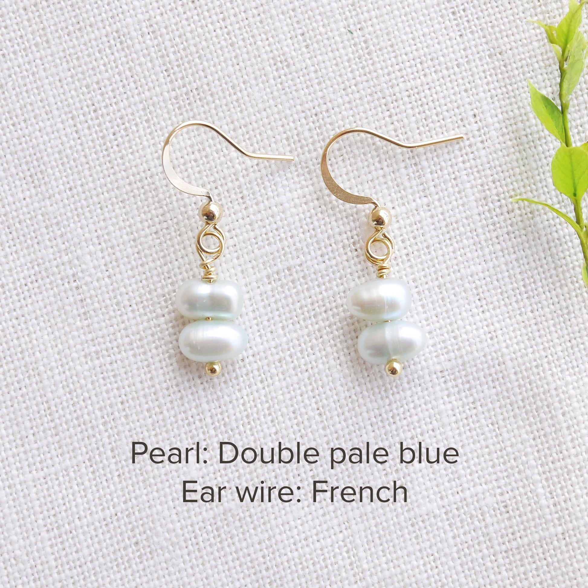 A pair of baroque freshwater pearl earrings on a white cloth.