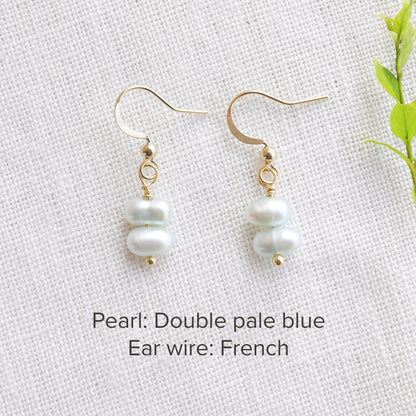 A pair of baroque freshwater pearl earrings on a white cloth.