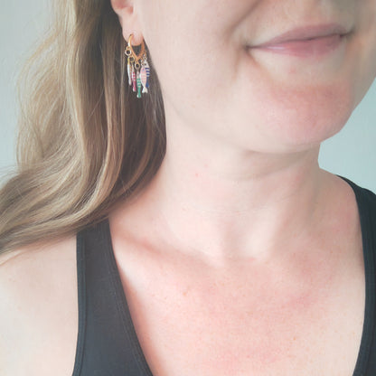Woman wearing fish charm hoop earrings.