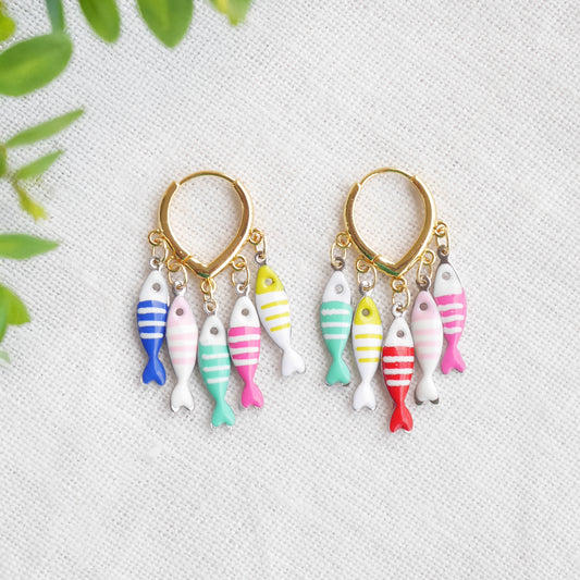 Fish charm hoop earrings on a white cloth.