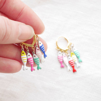 Fish charm hoop earrings on a white cloth.