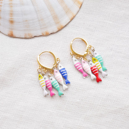 Fish charm hoop earrings on a white cloth.